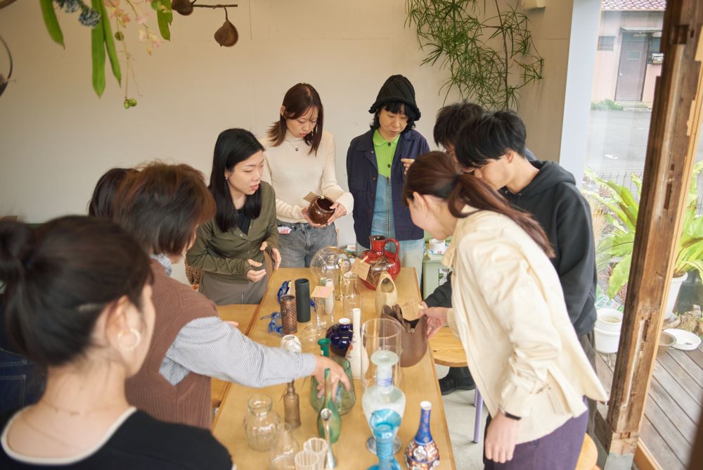 参加者9名が机を囲んで花瓶を選んでいる様子