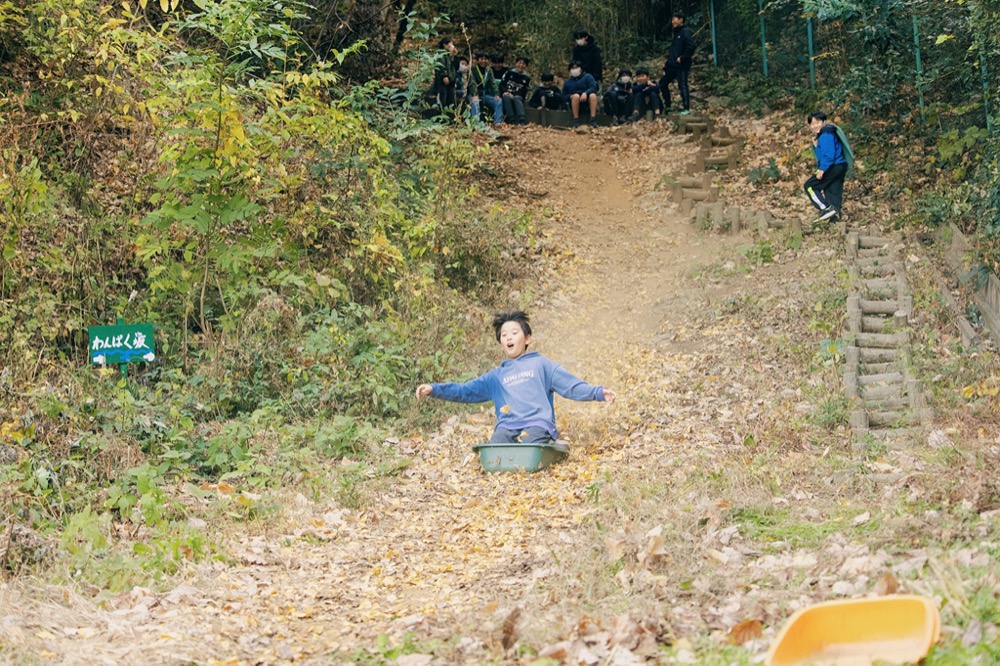 アスレの森で遊ぶ小学生たち。スライダーで滑り降りられるよう、坂道を整備した